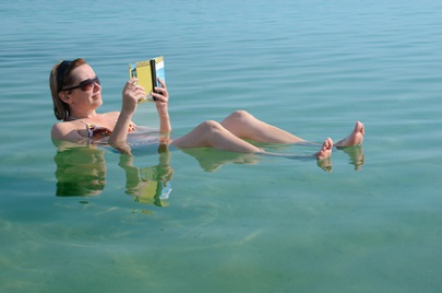 Frau liest Buch im toten Meer